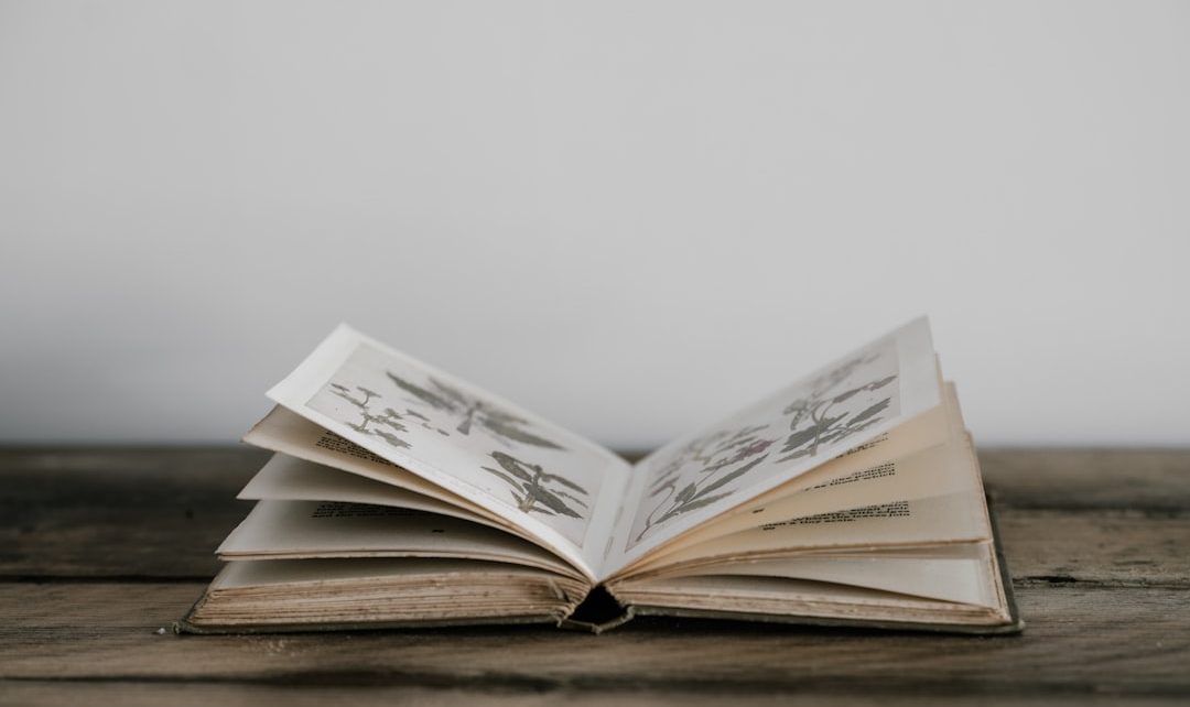 An open vintage book with illustrated pages on a wooden table.